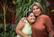 Portrait of mother embracing her daughter with special needs outdoors