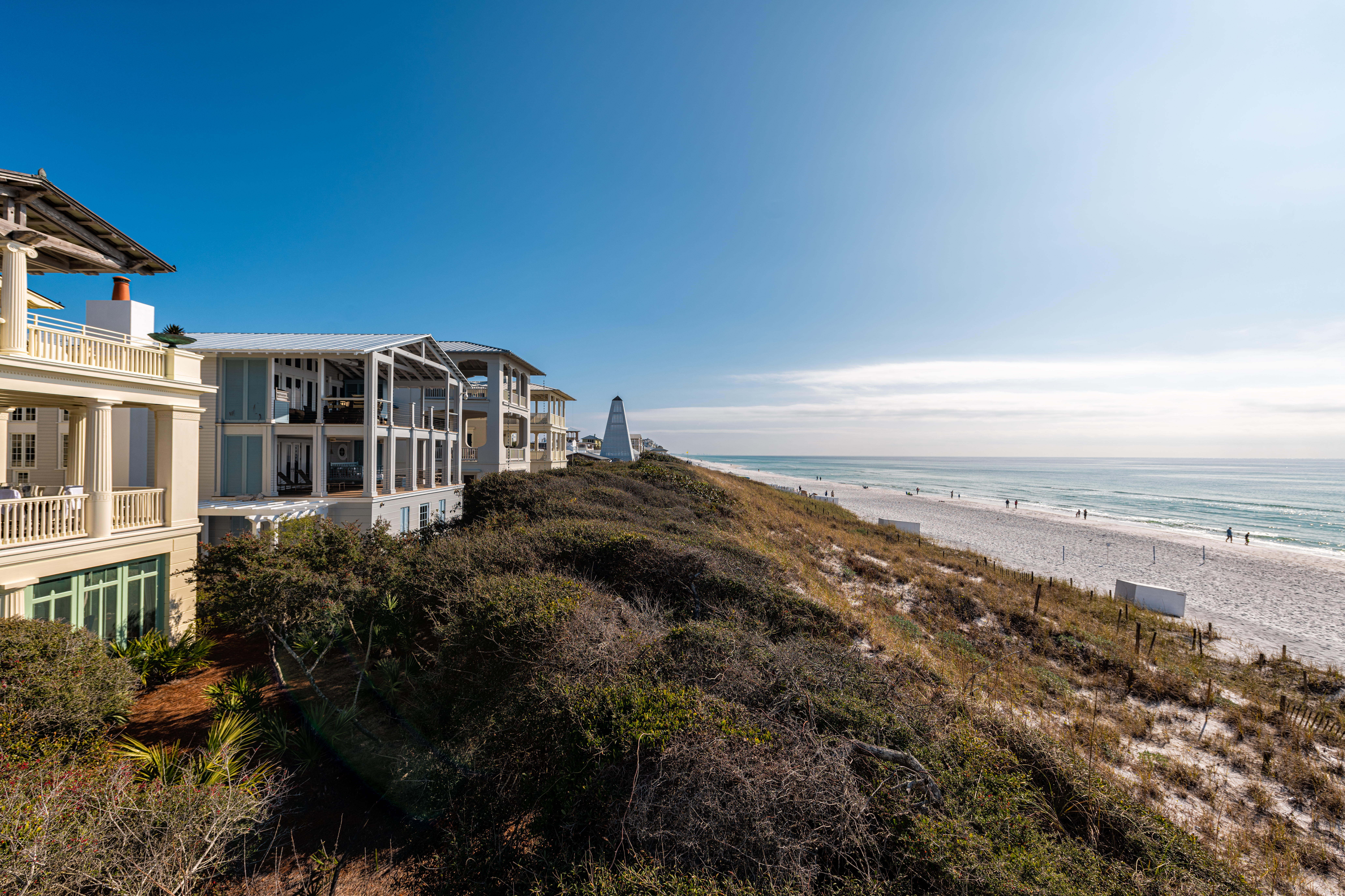 High angle view from wooden pavilion gazebo by beach at Gulf of Mexico at Seaside, Florida by new urbanism rental house home architecture with people walking on ocean sea coast