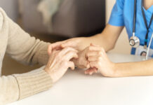 Young woman's hands hold grandmother's hands, an elderly patient. Handshake, caring, trust and support. Medicine, family and healthcare.
